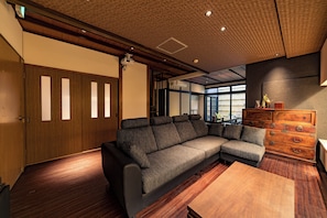 Un intérieur moderne avec un canapé d’angle, un plancher en bois et une commode en bois.