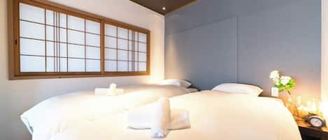Une chambre d’hôtel avec deux lits, une grande fenêtre et une table de chevet avec une lampe et une horloge.