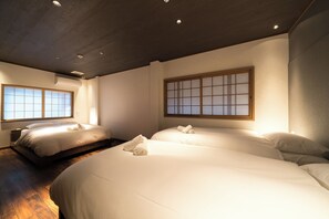 Une chambre d’hôtel avec deux lits, un plancher en bois et une porte coulissante traditionnelle.