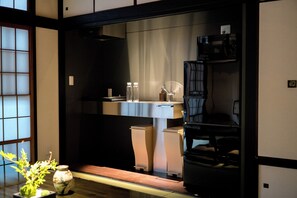 Ein traditioneller japanischer Raum mit Tatami-Boden, einem niedrigen Tisch mit Vase und einer Schiebetür.