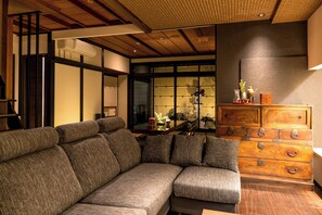 Ein modernes Wohnzimmer mit einem Ecksofa, einer Holzkommode und einem großen Fenster mit Blick.