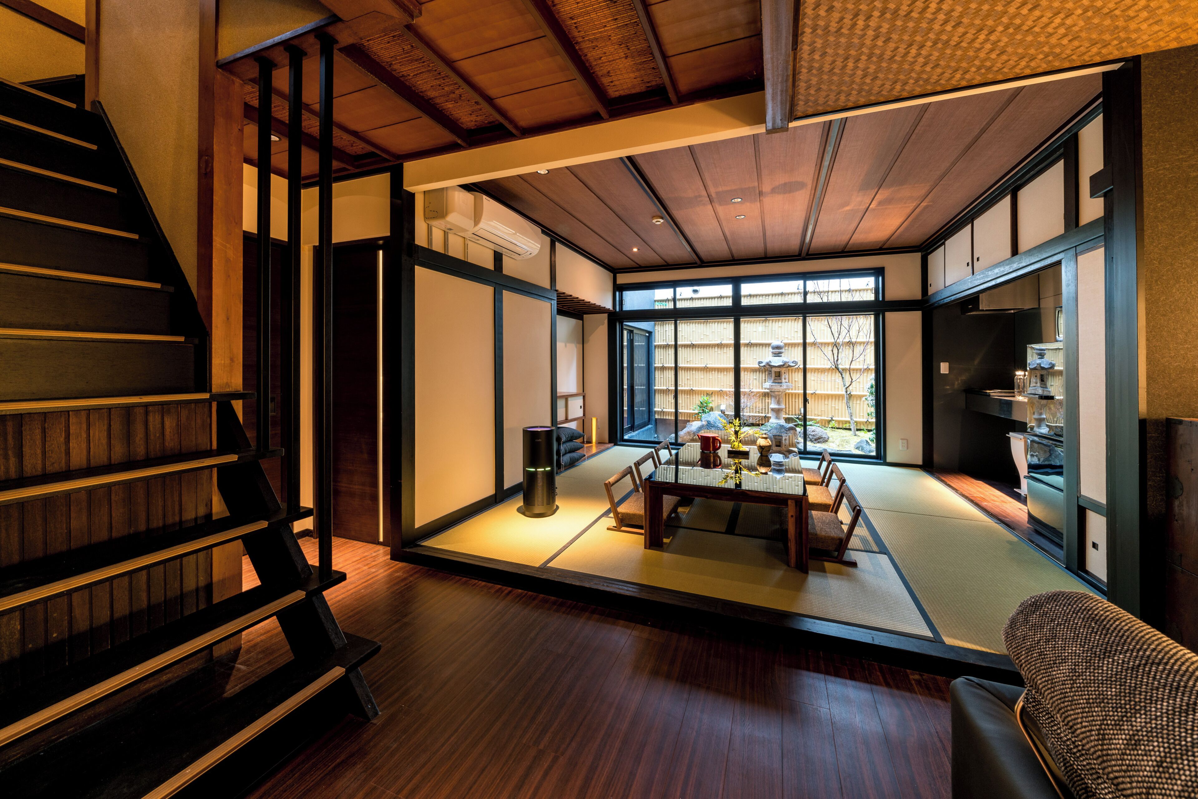 A traditional Japanese interior with tatami flooring, a low table, and a sofa.