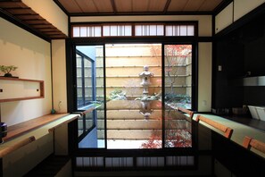 Ein traditioneller japanischer Raum mit Tatami-Boden, einer verschiebbaren Shoji-Schiebetür und Blick auf einen Garten mit einem Steingarten-Leuchter.