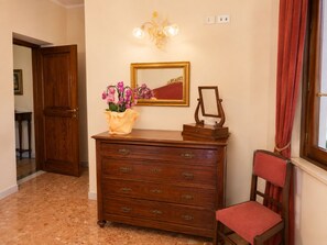 Eine Holzkommode mit Schubladen, ein Spiegel und ein Blumenstrauß in einer Diele mit einem roten Stuhl und einer Holztür.