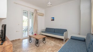 Una sala de estar con un sofá, una mesita y un televisor sobre un mueble de madera.