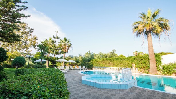 Un área de piscina con deck de azulejos, sillas de descanso y sombrillas.