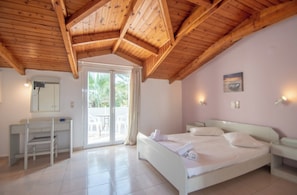 A bedroom with a wooden ceiling, a bed, a desk, and a sliding glass door leading to an outdoor area.