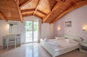 Un dormitorio con techo de madera, una cama, un escritorio y un ventanal corredizo que da a un espacio exterior.