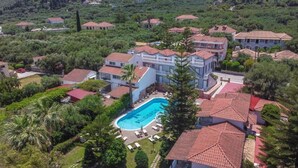 Un gran edificio residencial con piscina rodeada de abundante vegetación.