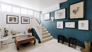 Ein Zimmer mit Treppe, einem Couchtisch, einem Globus, gerahmten Bildern an der Wand und einem Paar Stiefeln auf dem Boden.