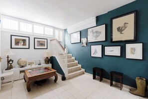 A room with a staircase, a coffee table, a globe, framed artwork on the wall, and a pair of boots on the floor. - Refined 1BDR Retreat in the Heart of Clapham (Greater London)