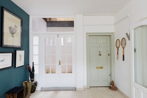 A hallway with a white door, a framed artwork, and a pair of tennis rackets on the wall. - Refined 1BDR Retreat in the Heart of Clapham (Greater London)