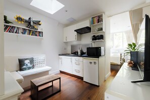 A compact kitchen with white cabinets, a microwave, and a coffee maker. - Refined 1BDR Retreat in the Heart of Clapham (Greater London)
