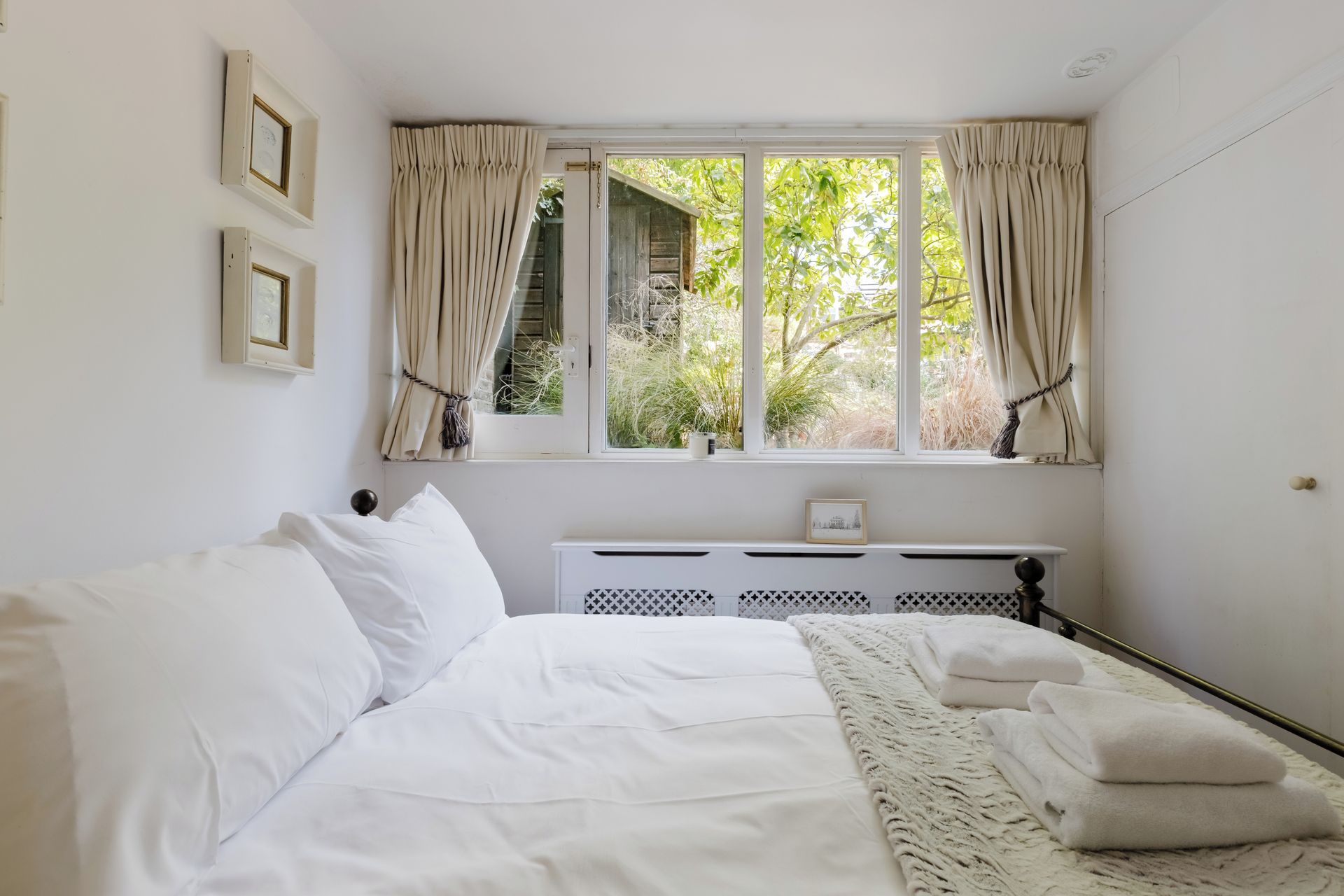 Une chambre avec un grand lit, un radiateur et une fenêtre avec des rideaux.