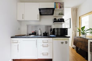 A compact kitchen with white cabinets, a black microwave, and a sink. - Refined 1BDR Retreat in the Heart of Clapham (Greater London)