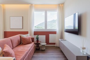 A modern living room with a sofa, a small table, a potted plant, and a flat-screen TV mounted on the wall. - Circle Bike Residence by Rent All Como. (Tavernerio)