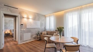 A modern living room with a round dining table, beige sofas, and a large window with sheer curtains. - Circle Bike Residence by Rent All Como. (Tavernerio)