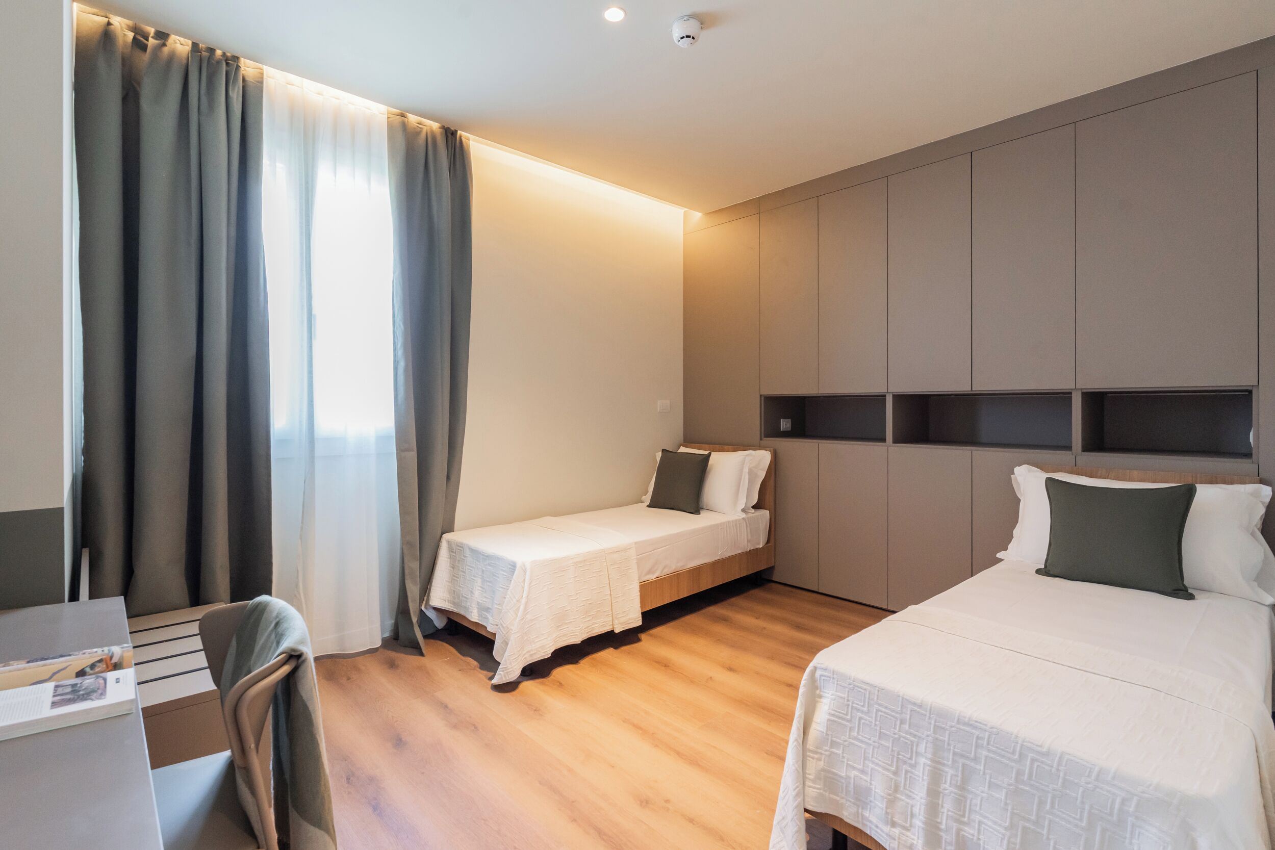 Ein Hotelzimmer mit zwei Betten, einem Schreibtisch und einem Sessel.