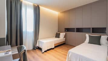 Ein Hotelzimmer mit zwei Betten, einem Schreibtisch und einem Sessel.