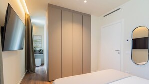 A hotel room with a bed, a wardrobe, a mirror, and a television on the wall. - Circle Bike Residence by Rent All Como. (Tavernerio)