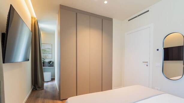 Ein Hotelzimmer mit Bett, Kleiderschrank, Spiegel und Fernseher an der Wand.