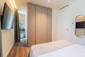Quarto de hotel com cama, guarda-roupa, espelho e televisão na parede.