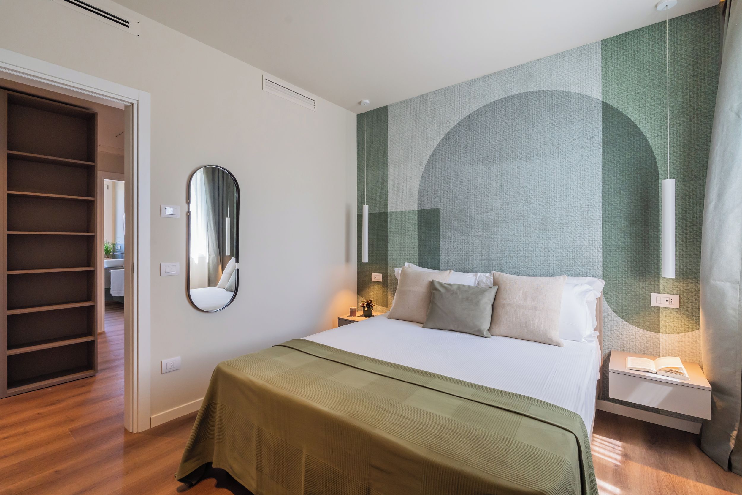 Ein Hotelzimmer mit einem Bett, einem Nachttisch, einem Schrank und einem Spiegel.