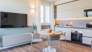 A modern kitchen with a dining area, a flat-screen TV mounted on the wall, and a Bosch oven. - Circle Bike Residence by Rent All Como. (Tavernerio)