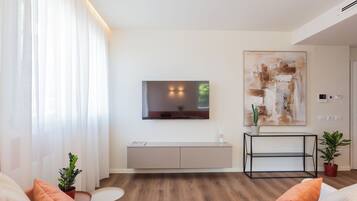 A modern living room with a flat-screen TV mounted on the wall, a minimalist console table, and a large abstract painting.