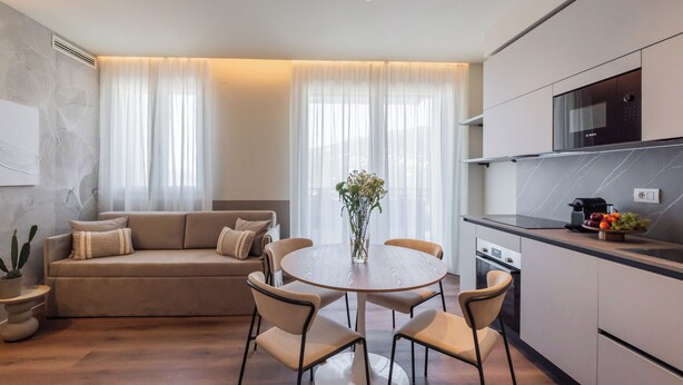A modern kitchen with a Bosch microwave, a dining area with a round table and chairs, and a living area with a sofa and a cactus plant. - Circle Bike Residence by Rent All Como. (Tavernerio)