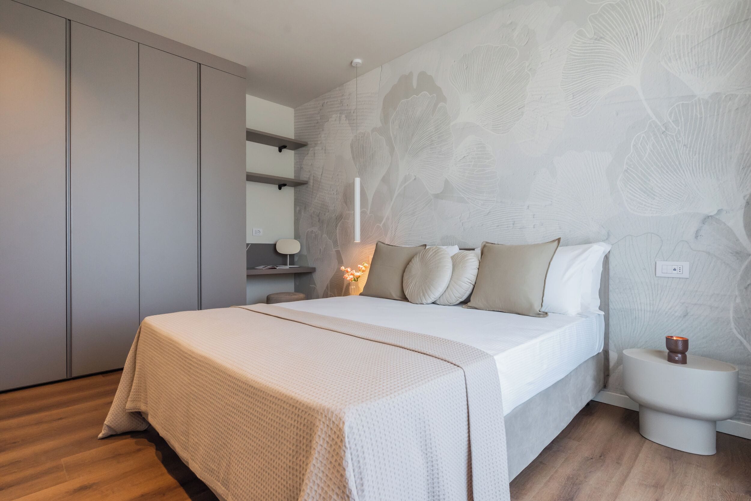 Un dormitorio con cama, mesitas de noche, armario y una pared con estampado floral.