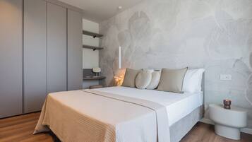 Un dormitorio con cama, mesitas de noche, armario y una pared con estampado floral.