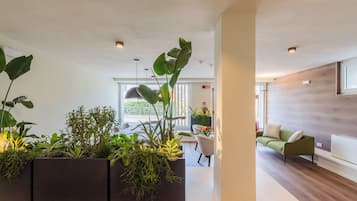 A modern interior with a reception desk, seating area, and a view of the outdoors.