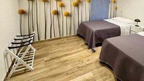 A room with two beds, a wooden floor, a wall-mounted drying rack, and a blue accent wall.