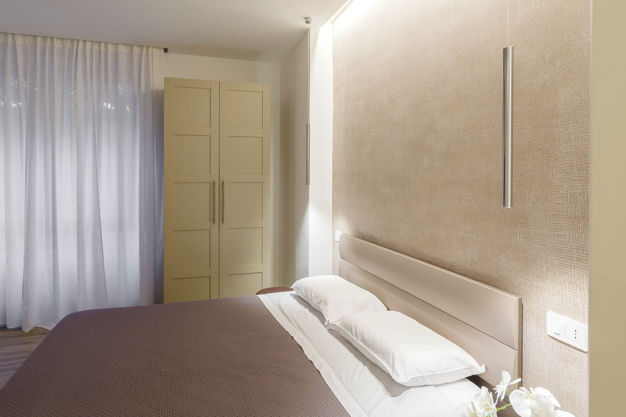 Une chambre d’hôtel équipée d’un lit, d’une armoire et d’un luminaire fixé au mur.