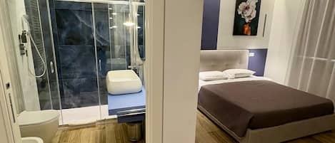 Un dormitorio moderno con cama, zona de ducha y baño.