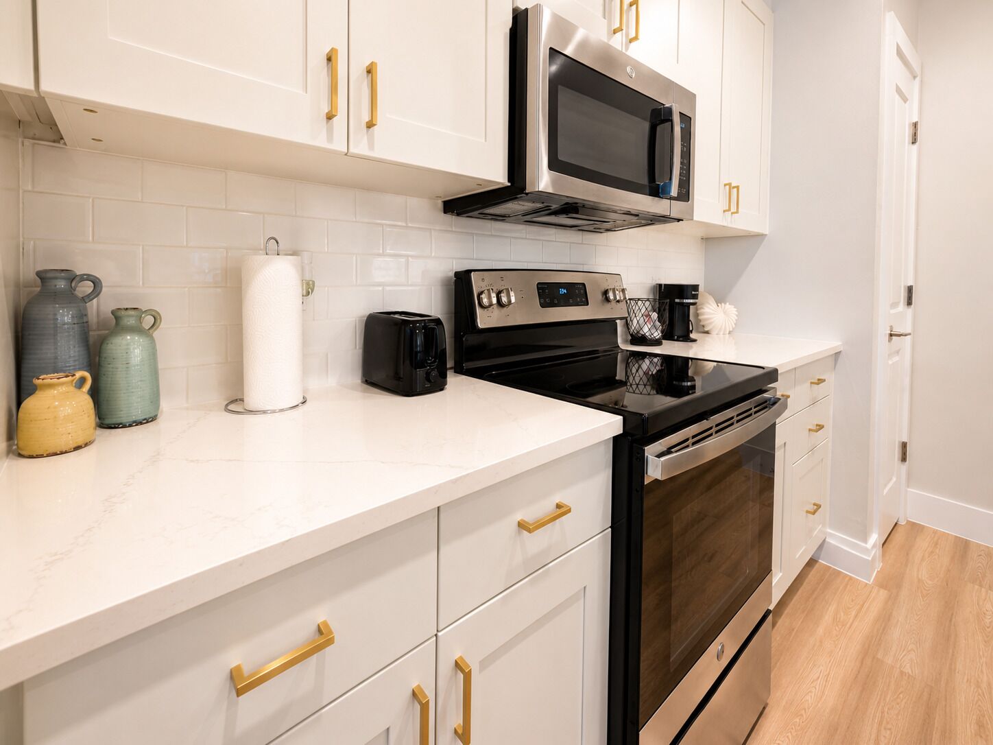A modern kitchen with white cabinetry, stainless steel appliances, and a marble countertop.