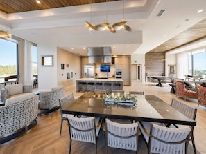 A modern kitchen with a central island, bar stools, and a dining area with a large table and chairs. - Luxury North Retreat with Pool and Gym (Naples)