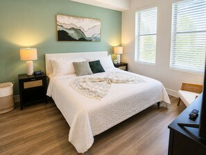 A neatly arranged bedroom with a bed, bedside tables, a lamp, a clock, and a painting on the wall. - Luxury North Retreat with Pool and Gym (Naples)