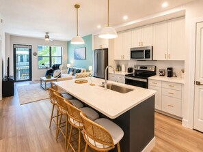 A modern kitchen with a central island, bar stools, and a dining area with a sofa and chairs. - Luxury North Retreat with Pool and Gym (Naples)