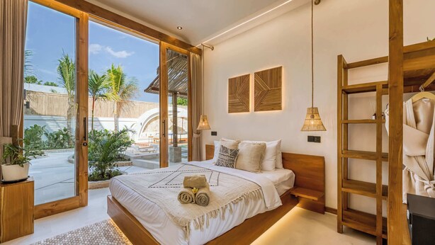 A bedroom with a large bed, a wooden headboard, a balcony with a view of palm trees, and a hanging chair. - Villa Provence, NEW 8BDR, Jacuzzi, Cinema, Luxury (Kabupaten Badung)