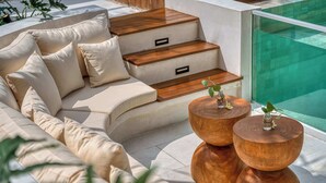 A modern outdoor seating area with a sofa, wooden steps, and two round wooden tables with plants. - Villa Provence, NEW 8BDR, Jacuzzi, Cinema, Luxury (Kabupaten Badung)