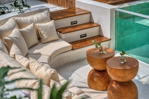 Ein moderner Außenbereich mit Sitzgelegenheit, einer Couch, Holzstufen und zwei runden Holztischen mit Pflanzen.