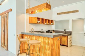 Eine moderne Küche mit Holzelementen, einer Bar und einer hängenden Leuchte.
