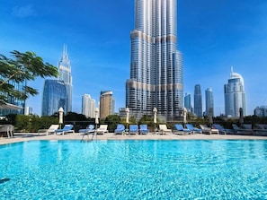 Ein Swimmingpool mit Liegestühlen und einer Stadtkulisse im Hintergrund.