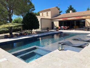 Une piscine dotée d’une terrasse ensoleillée, de chaises longues et d’un espace salon abrité.
