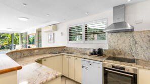 Eine moderne Küche mit Geschirrspüler, Backofen und einem Fenster mit Jalousien.