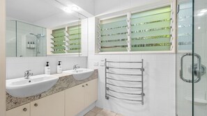 A modern bathroom with two sinks, a glass shower enclosure, and a towel rack. - Bahia Lindo 1 Noosa Heads (Noosa Heads)