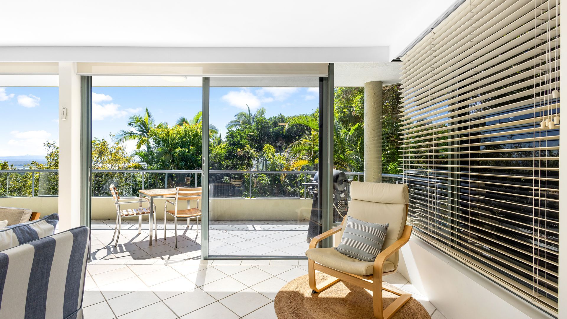 A balcony with a table and chairs, a sofa, and a window with blinds.