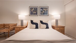 Ein Hotelzimmer mit einem großen Bett, zwei Nachttischen, einem Sessel und zwei Wandlampen.